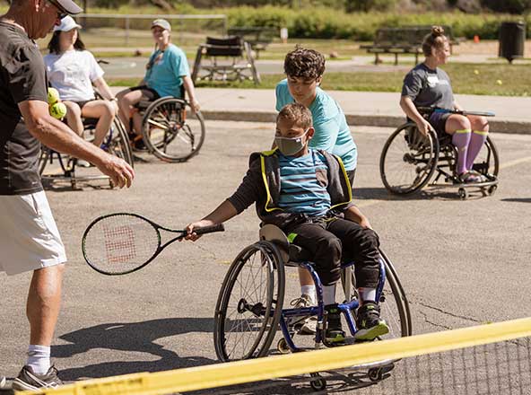 youth in wheelchairs playing tennis