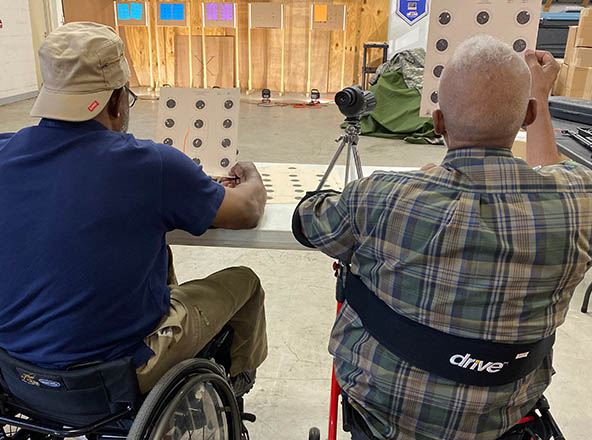 The back of 2 people in wheelchairs facing a target.