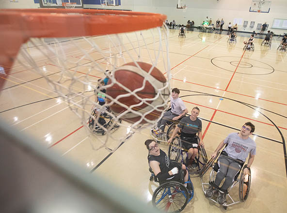 Basketball going through net with wheelchair players below.